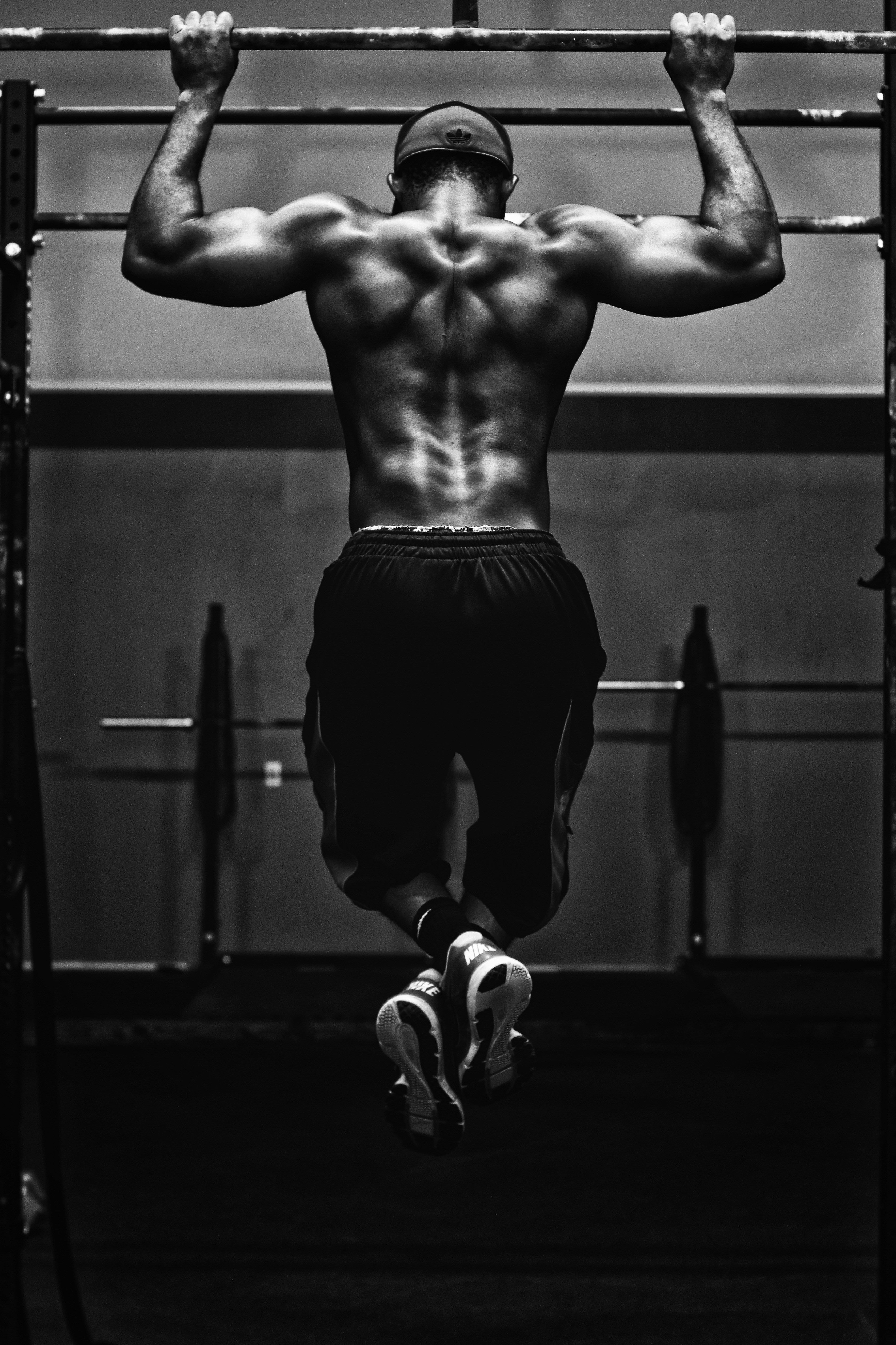 Muscular person performing pull-ups in a gym setting
